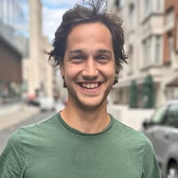 Portrait de Sébastien de Radiguès, souriant, en t-shirt vert dans une rue en ville