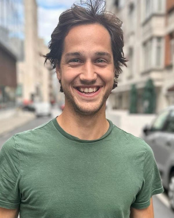 Portrait de Sébastien de Radiguès, souriant, en t-shirt vert dans une rue en ville